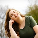 A carefree woman enjoying a sunny day outdoors, expressing pure happiness and relaxation.